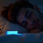 A thoughtful young adult lies in bed at dusk beside a softly glowing sleep tracker on the nightstand, bathed in warm and cool light.