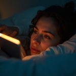 A person lies awake in a softly lit bedroom at night, surrounded by glowing sleep gadgets and relaxing in a serene, cozy atmosphere.